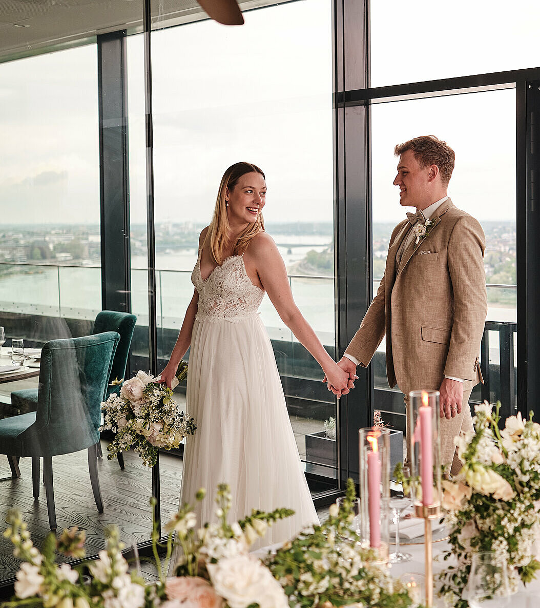 Hochzeitspaar läuft Hand in Hand durch Konrad's. Im Vordergrund sehen wir Hochzeitsdekoration auf dem Tisch